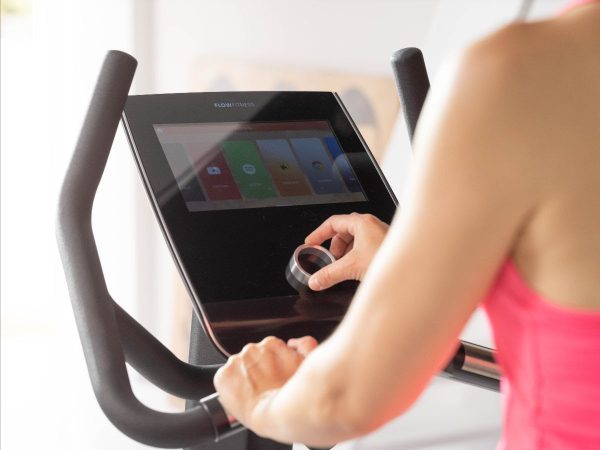 hometrainer B5s van Flow Fitness met 10,1 touchscreen bediend door een vrouw